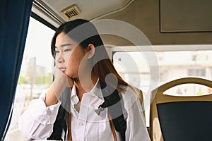 Young woman looking through looking through the window while commuting by bus