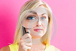 Young woman looking through a magnifying glass