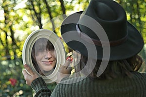 Young Woman Looking in the Mirror In Forest