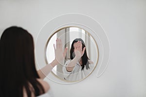 young woman looking in the mirror. Mental health problems in self-isolation at home. Depression, anxiety, phobia
