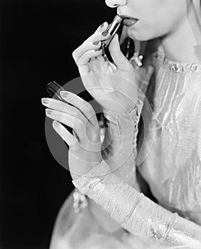 Young woman looking into a mirror and putting on make up