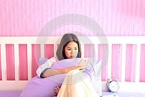 Young woman looking at mobile smart phone with feeling sad and crying in the bedroom, sadness emotion