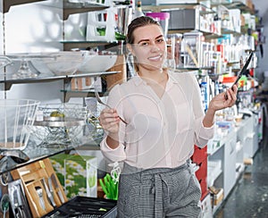 Young woman looking new cutlery sets in dinnerware shop