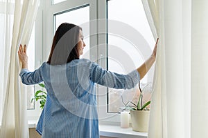 Young woman looking out window, cloudy winter day