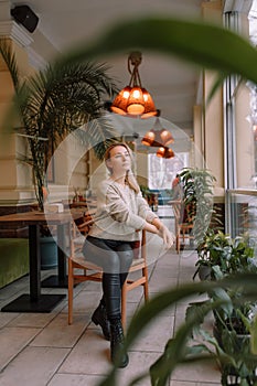 Young woman looking out the window while sitting in a chair on a winter day