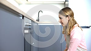 Young woman looking at oven, planning dishes for family dinner, housework