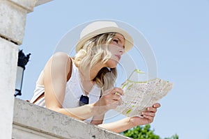 young woman looking over wall holding map