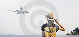 Young woman looking at plane flying above the sea panoramic banner. Travel, tourism, transportation concept