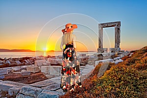 Young woman looking at Portara of Naxos island at sunset, Greece
