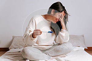 Young woman looking at pregnancy test with sad and desperate face. hispanic woman in her thirties smiling as concept of fertility