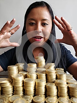 young woman looking at savings with the stacked coins of mexican pesos