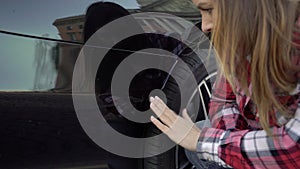 Young woman looking at scratch damage of her car bumper. Girl traffic accident