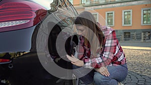 Young woman looking at scratch damage of her car bumper. Girl traffic accident