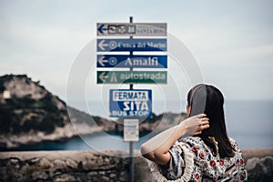 Young woman looking at sign table for direction.Wman on vacation in Italian coast.South cosat of Italy, Amalfi and Positano sights