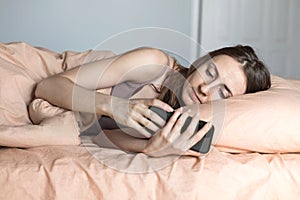 Young woman looking at smart phone screen in bed