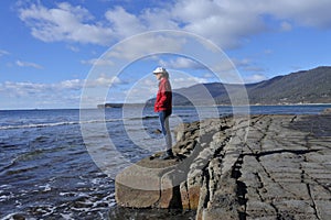 Young woman hiking over the Tessellated Pavement in Tasman Peninsula Tasmania Australia photo