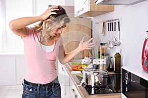 Young Woman Looking At Spilling Out Boiled Milk From Utensil