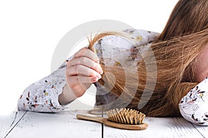 Young woman looking at split ends. Damaged long hair