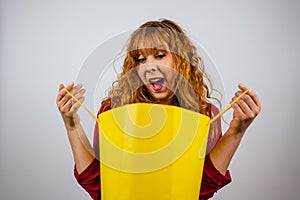 Young woman looking surprised at a shopping bag on a white background