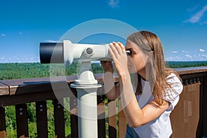 Young woman looking through tourist sightseeing binoculars