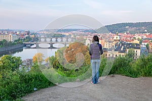 Young woman looking at the Vltava river and bridges of Prague