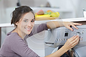young woman looking into washing machine