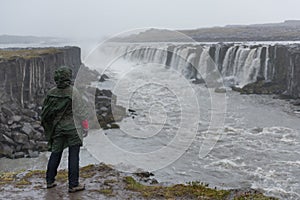 A young woman looking at a waterfall, Iceland