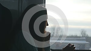 Young woman looking on window during riding on train. Profile of attractive girl travelling on railroad. Close up