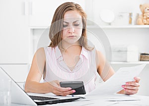 Young woman looking worriedly at bills