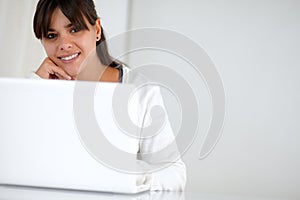 Young woman looking at you in front of her laptop