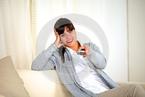 Young woman looking at you with tv remote