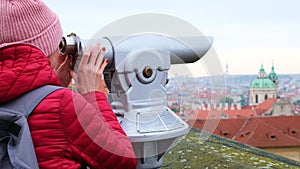 Young woman looks binoculars through coin binocular city street Panorama City