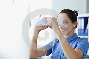 Young woman looks through binoculars made of paper