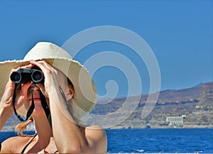 Young woman  looks through binoculars at sea