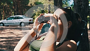 Young Woman Looks Through Binoculars While Sitting on a Chaise Longue in Nature