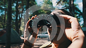 Young Woman Looks Through Binoculars While Sitting on a Chaise Longue in Nature