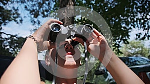 Young Woman Looks Through Binoculars While Sitting on a Chaise Longue in Nature