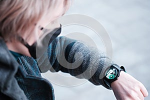 A young woman looks at her watch with an emblem of ecology