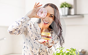 Young woman looks through a hole in one of donuts she holds in front of her