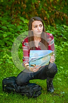 A young woman looks at a map while hiking.