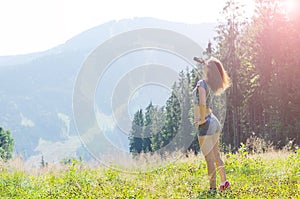 Young woman looks at the mountains through binoculars, outdoor a