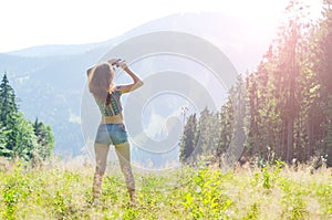 Young woman looks at the mountains through binoculars, outdoor a