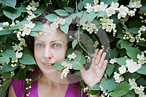 Young woman looks out from blooming jasmine bush