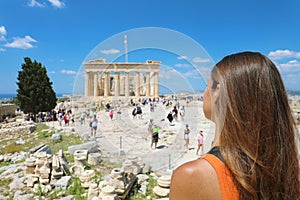 Young woman looks at Parthenon on the Acropolis of Athens, Greece. The famous ancient Greek Parthenon is the main tourist