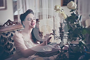 Young woman looks at a photo album. Vintage style, retro interior