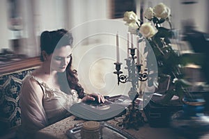 Young woman looks at a photo album. Vintage style, retro interior