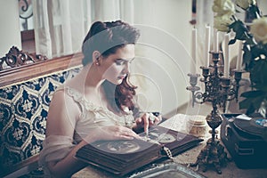 Young woman looks at a photo album. Vintage style, retro interior