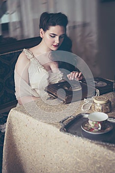 Young woman looks at a photo album. Vintage style, retro interior.