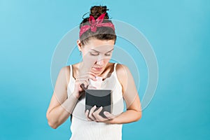 A young woman looks into a piggy bank, where she puts or takes a ten euro