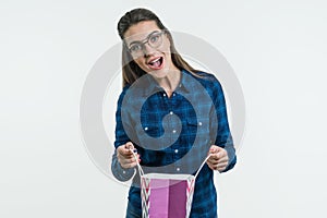 A young woman looks in surprise at the shopping bag. White Background Studio